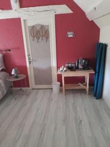 a bedroom with red walls and a table and a door at l orchidee in Hérisson