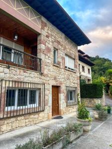 a stone house with a wooden door and a balcony at Pensión El Campanu in Cangas de Onís