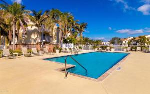 una piscina con sedie e palme di Luxury Beachside Condo - Half Mile from Beach a Indialantic