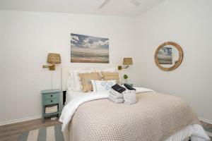una camera da letto bianca con un letto e uno specchio di Luxury Beachside Condo - Half Mile from Beach a Indialantic Altre 17 foto