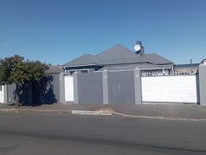 een huis met een hek en een witte garage bij The trout Lodge in Kaapstad