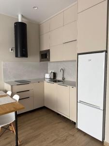 a kitchen with white cabinets and a white refrigerator at WHITE HORTENZIA Guesthouse in Batumi