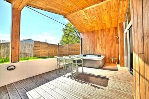 a patio with a tub and a table on a deck at Maison cosy avec spa extérieur et vélos électriques in Mortagne-sur-Gironde