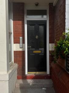 a black front door of a brick house at Reads Avenue - Luxury Ground Floor Studio - Next Door to H&A Social Club in Blackpool