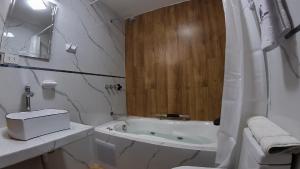a white bathroom with a tub and a sink at Hotel Rosa Mistika Inn in Arequipa