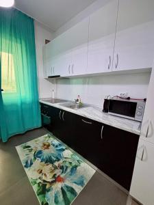 een keuken met witte kasten, een wastafel en een tapijt bij The Palas Retreat in Iaşi