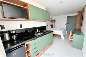 a kitchen with green cabinets and a sink and a bed at Beach Way c/Piscina na cobertura-Miramar Hospedagens in João Pessoa