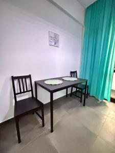 een tafel en 2 stoelen in een kamer met blauwe gordijnen bij The Palas Retreat in Iaşi