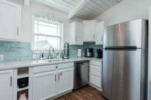 een keuken met witte kasten en een roestvrijstalen koelkast bij Someday Isle - 2BDR Home for 6 in Port Aransas