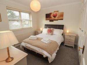 a bedroom with a bed and a lamp and a window at Riverside Cottage in Cockermouth