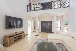 a living room with a white couch and a tv at Villa Montana in Tarcoles