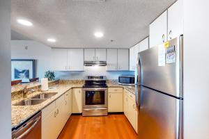 a kitchen with white cabinets and a stainless steel refrigerator at Triton's Trumpet B 303 in Ocean City