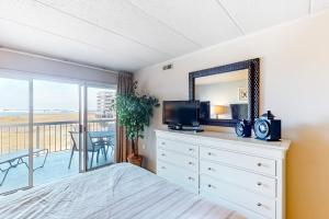 a bedroom with a dresser with a mirror and a balcony at Triton's Trumpet B 303 in Ocean City +7 photos