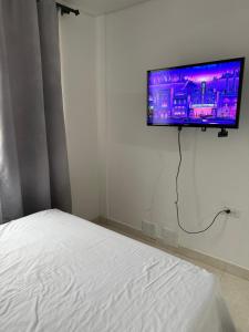 TV de pantalla plana colgada en una pared sobre una cama en Apartamento completo en el sur de Buga, en Buga