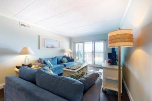 a living room with two blue couches and a lamp at Pelican Beach 304 in Ocean City