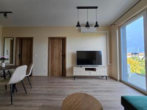 Una sala de estar con un televisor de pantalla plana y una mesa. en Apartament Odrzańskie Tarasy, Klimatyzacja, PW INVEST HOME, en Krapkowice