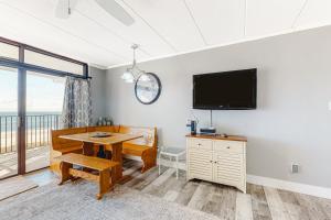 a dining room with a table and a flat screen tv at Sails II 502 in Ocean City