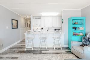 a kitchen with white cabinets and stools in a living room at Sails II 502 in Ocean City