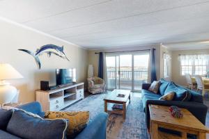 a living room with blue furniture and a dolphin painting on the wall at White Marlin 307B in Ocean City