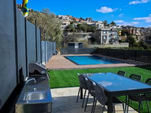 a patio with a table and a grill and a pool at Vista royal golan in Ein Kinya +10 photos