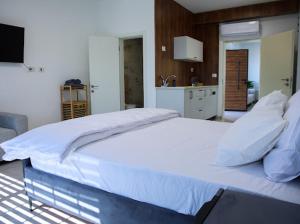 a large white bed in a room with a kitchen at Vista royal golan in Ein Kinya