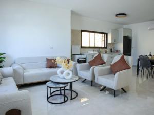 a living room with couches and a table and a kitchen at Vista royal golan in Ein Kinya