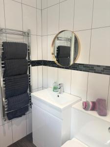 Un baño blanco con lavabo y espejo. en Phat Smokehouse, en Abertillery