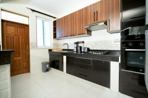 a kitchen with black appliances and wooden cabinets at Marhaba Tausi Nyali in Mombasa