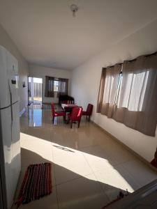 a living room with a table and red chairs at Casinha Aconchegante in Primavera do Leste