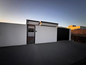 a white garage with a gate and a building at Casinha Aconchegante in Primavera do Leste