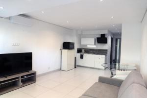 a living room with a couch and a television at L'Orée du Golf in Mandelieu-La Napoule