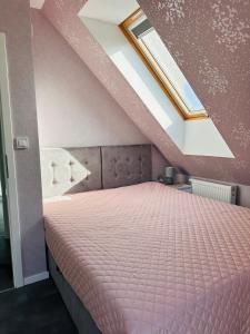 a bedroom with a pink bed in a attic at SOFIA Sol & Golden Dunes House in Trzęsacz
