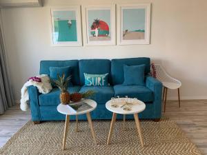 a blue couch in a living room with two tables at Chic Maui Condo Steps From Beach & Ocean in Wailea