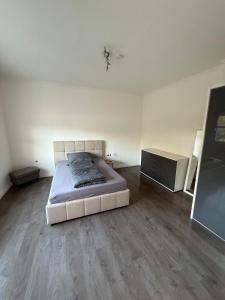 a white room with a bed and a dresser in it at Flexi Flats Vermietung in Lingen