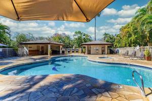 a swimming pool in a yard with an umbrella at Chic Maui Condo Steps From Beach & Ocean in Wailea