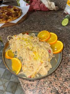 a plate of noodles and orange slices on a counter at Miral Camp in Nuweiba +8 photos