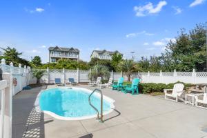 a swimming pool with chairs and a white fence at Wahoo Waves in Emerald Isle