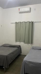 a room with two beds and a window with a curtain at VARANDA LENÇÓIS in Barreirinhas