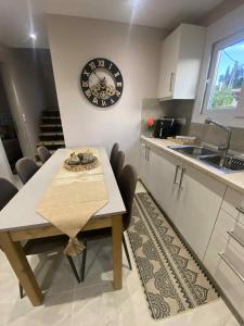 Una cocina con una mesa y un reloj en la pared. en The 50 50 Deluxe Apartments, en Sidari