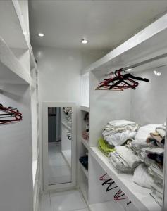 a white walk in closet filled with lots of clothes at Conheça Salvador na melhor localização in Salvador