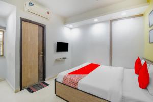 a bedroom with a bed with red pillows and a door at Super hotel O Adri 2 in Kolkata