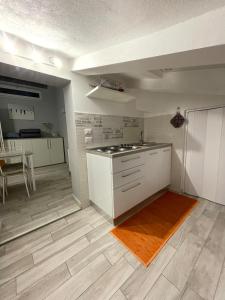 a kitchen with white cabinets and a wooden floor at Lovely apartment near the beach in Follonica