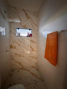 a bathroom with an orange towel hanging on the wall at Casinha Aconchegante in Primavera do Leste +6 photos