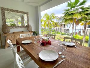 a wooden table with plates and glasses and a mirror at Tahiti Beach Loft - Pool - private beach access in Paea