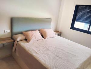 a bedroom with a bed with pink pillows on it at Dream apartment in Isla Plana in Mazarrón