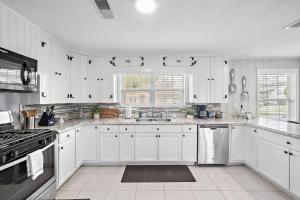 a large white kitchen with white cabinets and appliances at Baytown Getaway Patios BBQ Family-Friendly in Baytown