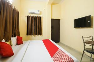 ラクナウにあるHotel O Laavin Inn Near Gomti Riverfront Parkのベッドルーム(赤い枕のベッド1台、テレビ付)