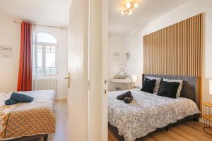 a bedroom with two beds and a window at Gatsby - Appartement rénové élégant, Hypercentre Saintes, Calme, Fibre, TV 4K, Netflix in Saintes