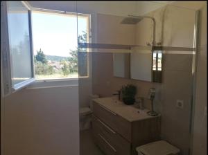 un bagno bianco con un lavandino e una finestra di Suite parentale avec terrasse solarium a Saint-André-de-Roquelongue