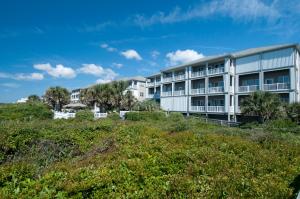 an apartment building on a hill with trees and bushes at Ocean Club J-301 in Indian Beach